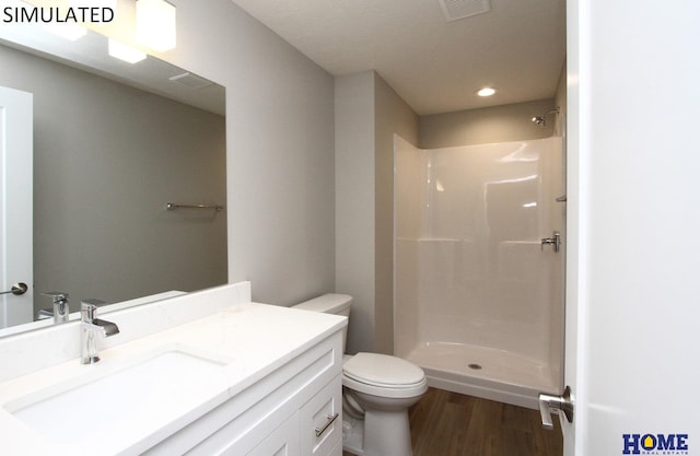 bathroom featuring toilet, wood finished floors, vanity, visible vents, and walk in shower