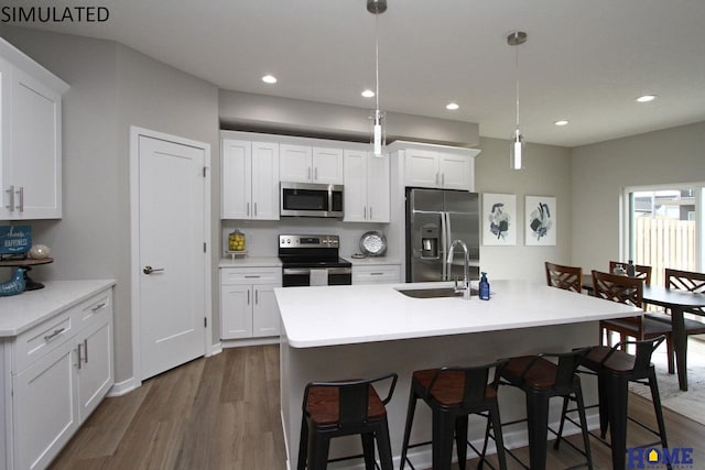 kitchen with dark wood-style floors, a breakfast bar area, stainless steel appliances, white cabinetry, and a sink