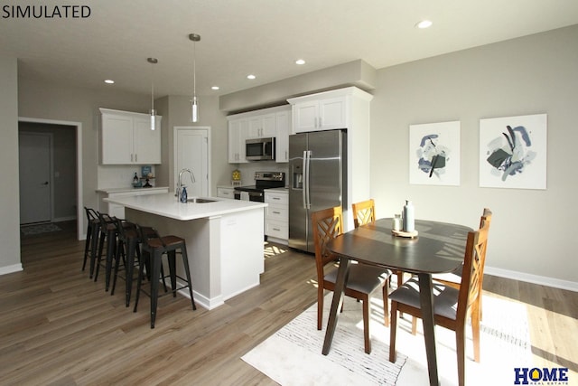 kitchen featuring light wood-type flooring, a kitchen island with sink, appliances with stainless steel finishes, and a sink