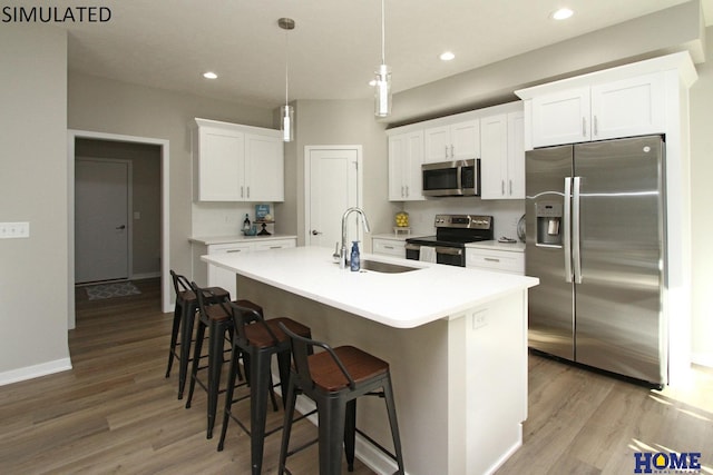 kitchen with stainless steel appliances, wood finished floors, an island with sink, and a sink