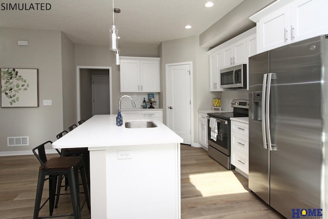 kitchen featuring appliances with stainless steel finishes, a sink, visible vents, and white cabinets