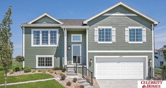 bi-level home with driveway, an attached garage, and fence