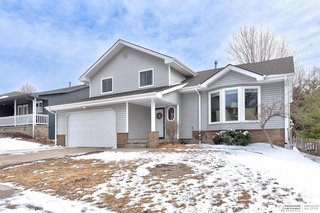 split level home with a garage, a porch, and a shingled roof