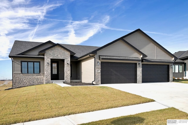 view of front of property with a shingled roof, an attached garage, stone siding, driveway, and a front lawn