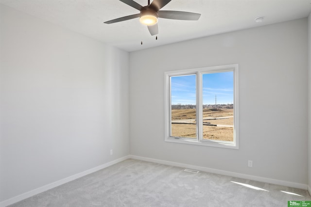 spare room featuring light carpet, visible vents, baseboards, and ceiling fan