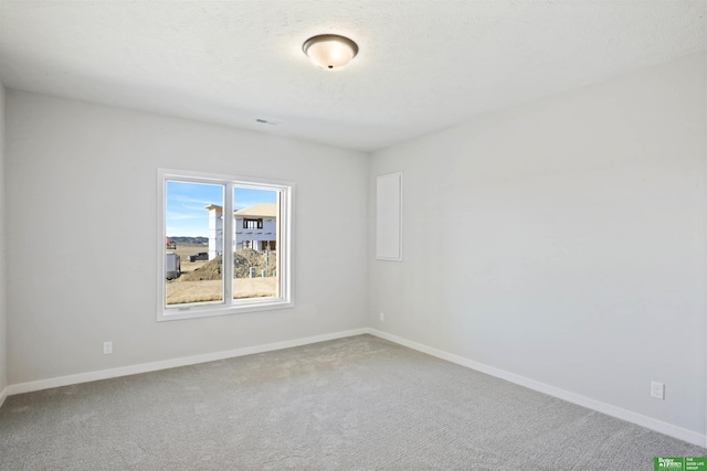 carpeted empty room featuring visible vents, a textured ceiling, and baseboards