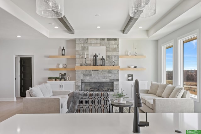 living area featuring recessed lighting, baseboards, beamed ceiling, and a stone fireplace