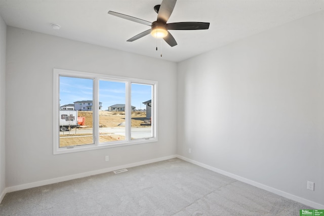 empty room featuring ceiling fan, light colored carpet, and baseboards