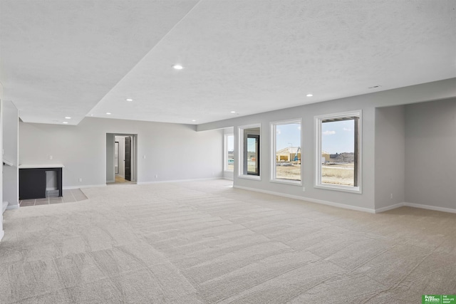 unfurnished living room with light carpet, baseboards, and recessed lighting