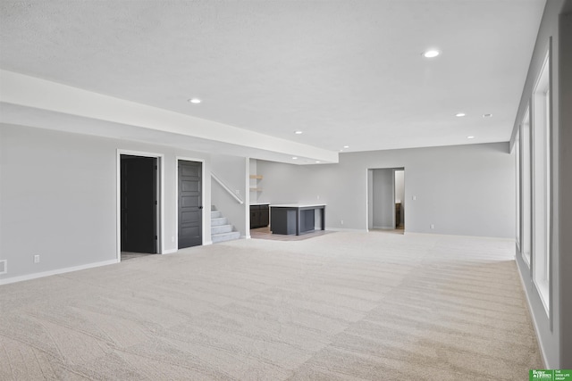 unfurnished living room featuring baseboards, stairway, recessed lighting, and light colored carpet