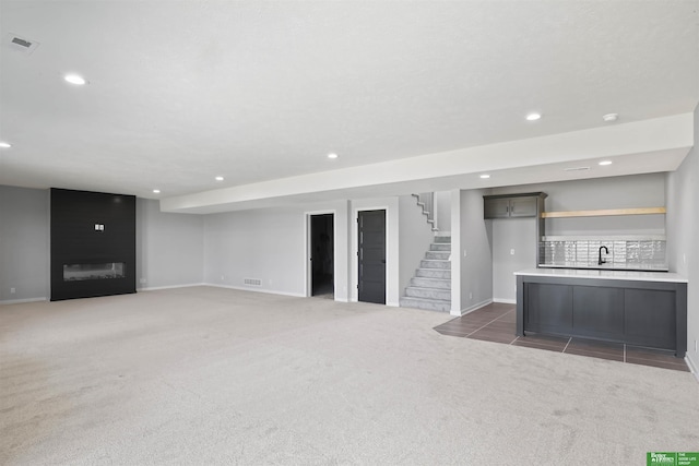 unfurnished living room featuring recessed lighting, visible vents, a large fireplace, carpet flooring, and stairs