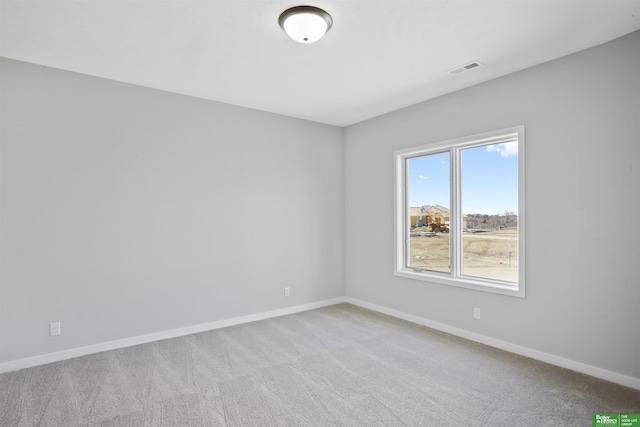 empty room with carpet, visible vents, and baseboards