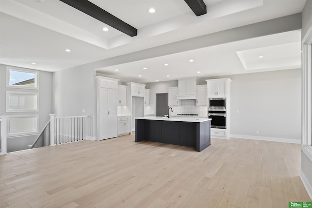 kitchen featuring a sink, white cabinets, beam ceiling, decorative backsplash, and light wood finished floors
