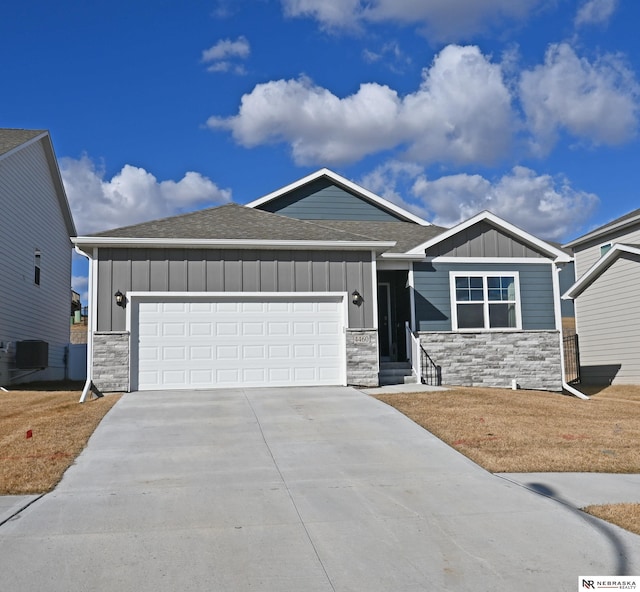 view of front of property featuring a garage, concrete driveway, stone siding, roof with shingles, and board and batten siding