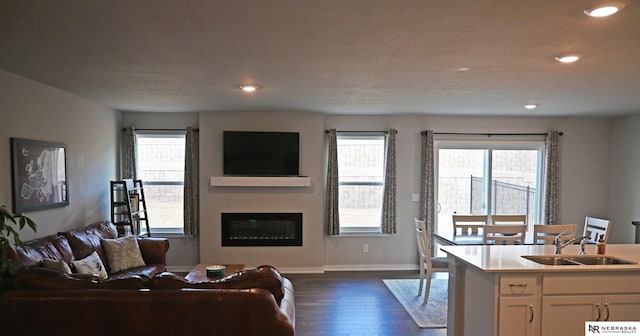 living room with recessed lighting, a glass covered fireplace, dark wood finished floors, and a healthy amount of sunlight