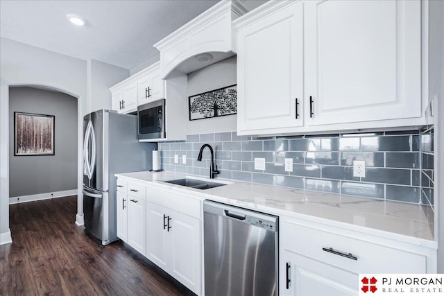 kitchen featuring stainless steel appliances, a sink, white cabinetry, and light stone countertops