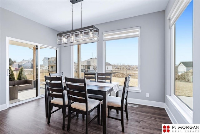 dining room featuring dark wood-style floors, visible vents, baseboards, and a chandelier