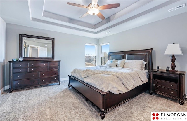 bedroom featuring baseboards, visible vents, a raised ceiling, light colored carpet, and ceiling fan