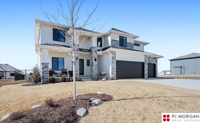 view of front of house with stucco siding, a porch, an attached garage, stone siding, and driveway