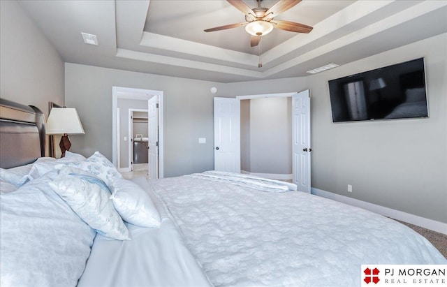 bedroom featuring ceiling fan, visible vents, baseboards, and a raised ceiling