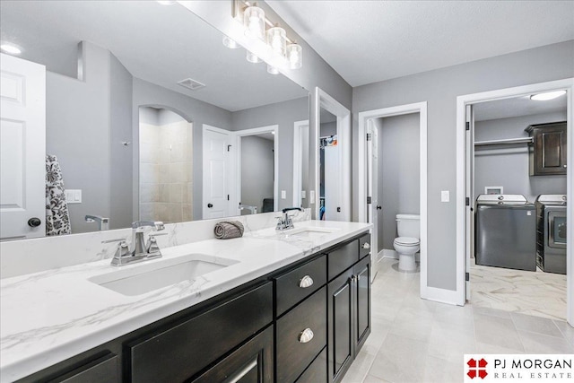 bathroom featuring toilet, visible vents, a sink, and washing machine and clothes dryer