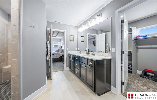 ensuite bathroom featuring double vanity, visible vents, a sink, a textured ceiling, and ensuite bath