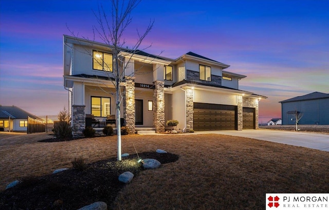 view of front of home featuring a porch, stone siding, concrete driveway, and stucco siding