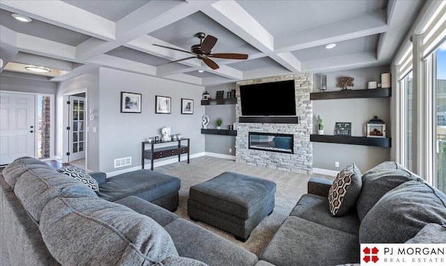 living room featuring baseboards, visible vents, coffered ceiling, a stone fireplace, and beam ceiling