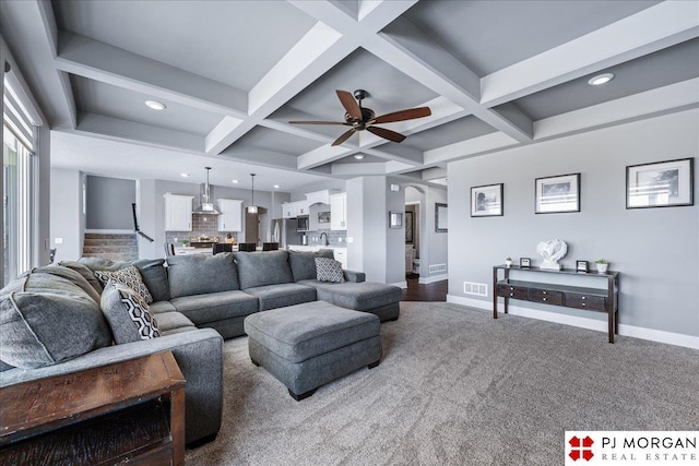 living area featuring baseboards, visible vents, coffered ceiling, and beamed ceiling