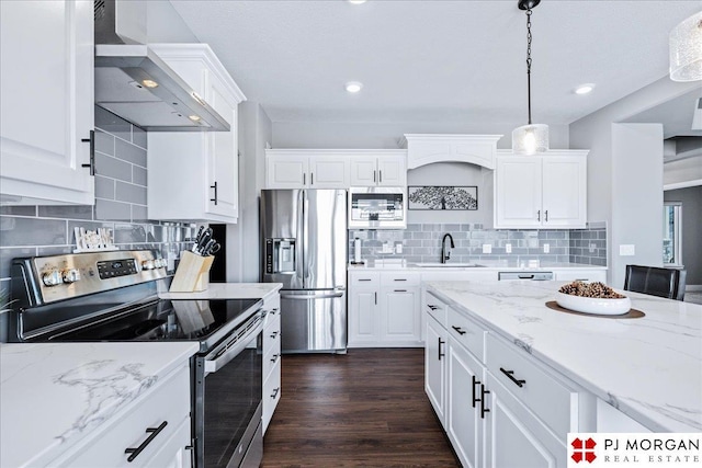 kitchen with appliances with stainless steel finishes, white cabinets, a sink, and wall chimney range hood