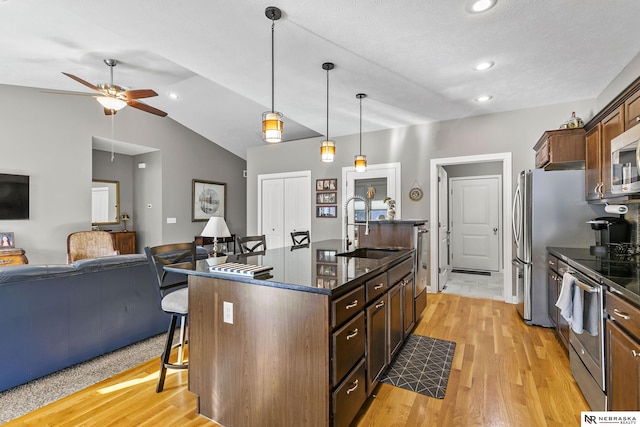 kitchen featuring a center island with sink, a breakfast bar, light wood-style floors, stainless steel appliances, and a sink