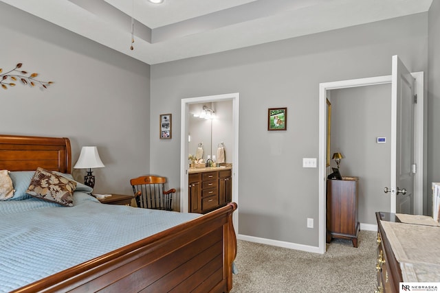 bedroom featuring a sink, baseboards, light carpet, and connected bathroom