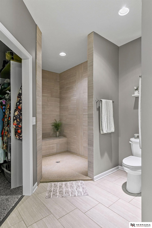 full bath featuring toilet, recessed lighting, baseboards, and tiled shower