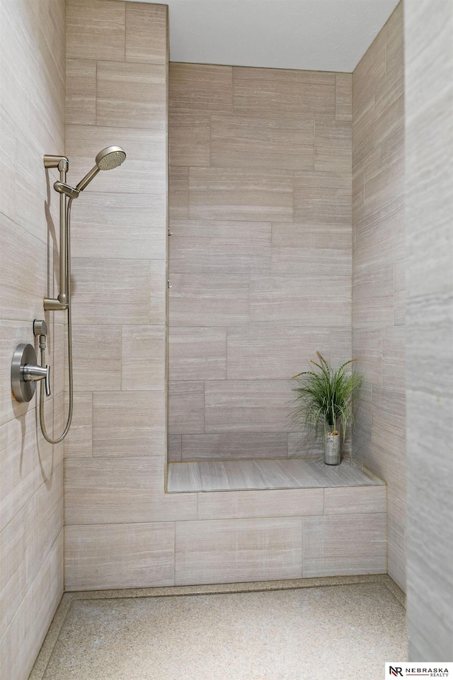 bathroom featuring speckled floor and a tile shower