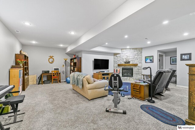 carpeted living area with recessed lighting, baseboards, and a stone fireplace