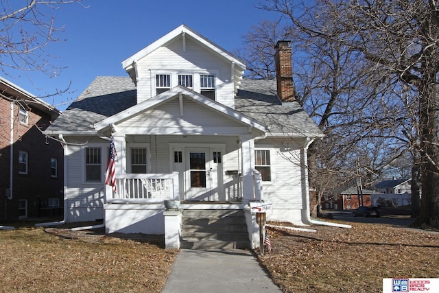 bungalow-style house with covered porch, a shingled roof, and a chimney