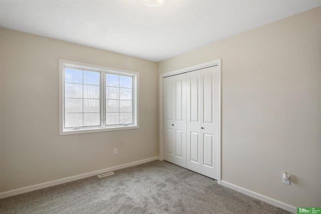 unfurnished bedroom with carpet floors, a closet, visible vents, and baseboards