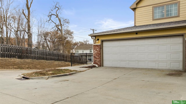 garage featuring driveway and fence