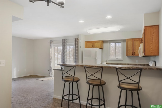 kitchen featuring carpet floors, white appliances, plenty of natural light, and a peninsula