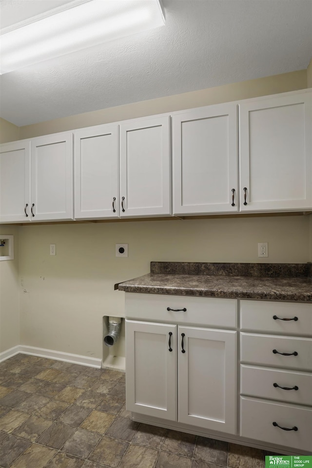 laundry room with washer hookup, baseboards, cabinet space, stone finish floor, and electric dryer hookup