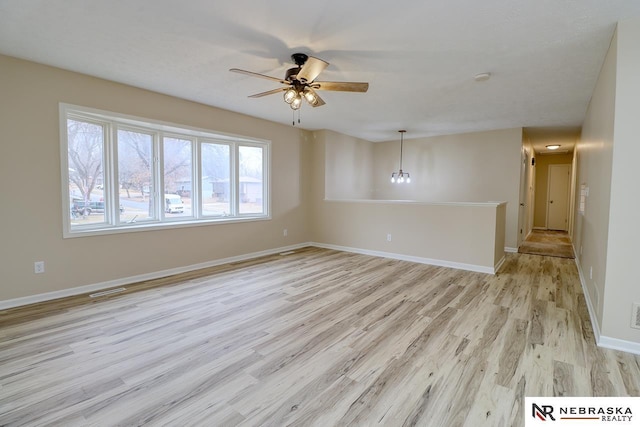 unfurnished room with visible vents, light wood-type flooring, a ceiling fan, and baseboards