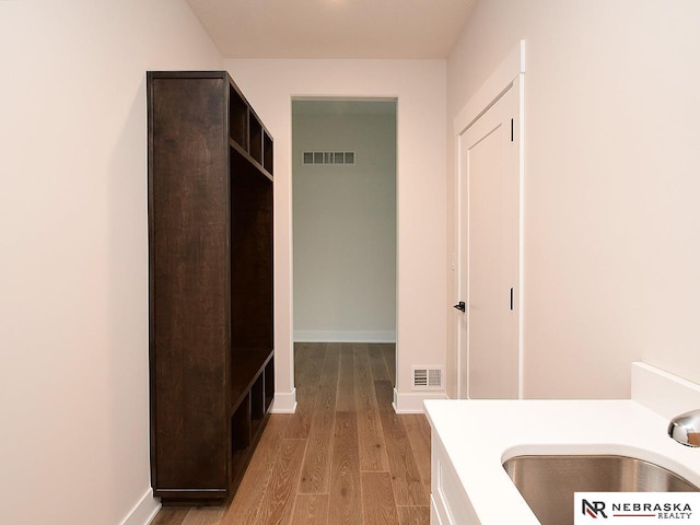 bathroom with a sink, baseboards, visible vents, and wood finished floors