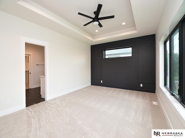 spare room featuring recessed lighting, baseboards, a tray ceiling, and light colored carpet