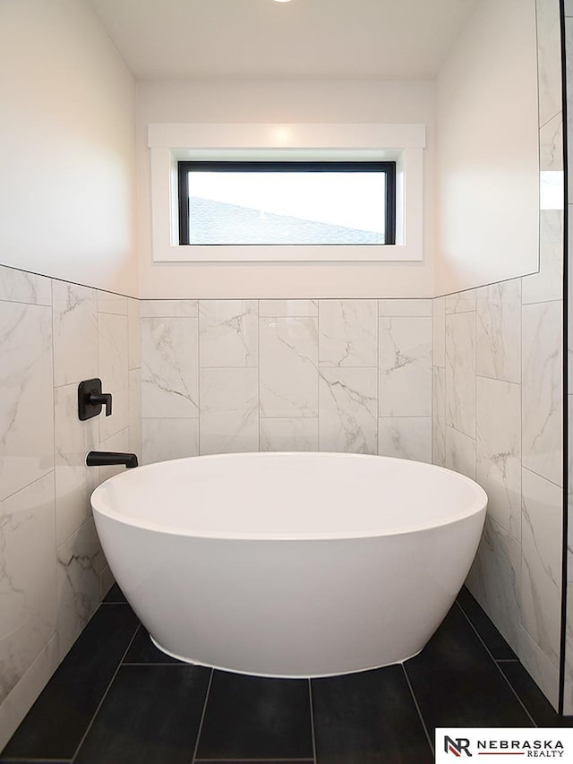 full bath with a freestanding bath, a wealth of natural light, and tile patterned floors