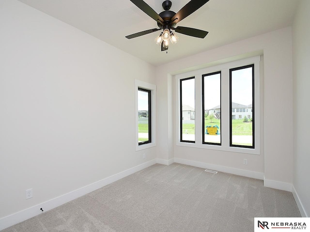 empty room featuring baseboards, a ceiling fan, and light colored carpet