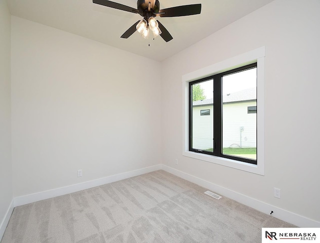 spare room with baseboards, a ceiling fan, visible vents, and light colored carpet