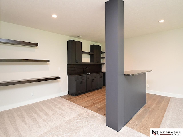 kitchen featuring open shelves, recessed lighting, a sink, light wood-type flooring, and baseboards