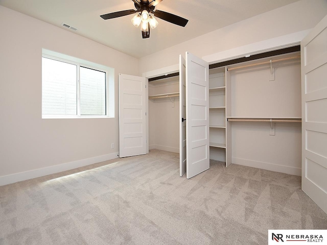 unfurnished bedroom with light carpet, a ceiling fan, baseboards, visible vents, and multiple closets