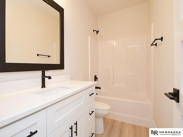 bathroom featuring washtub / shower combination, vanity, wood finished floors, and toilet