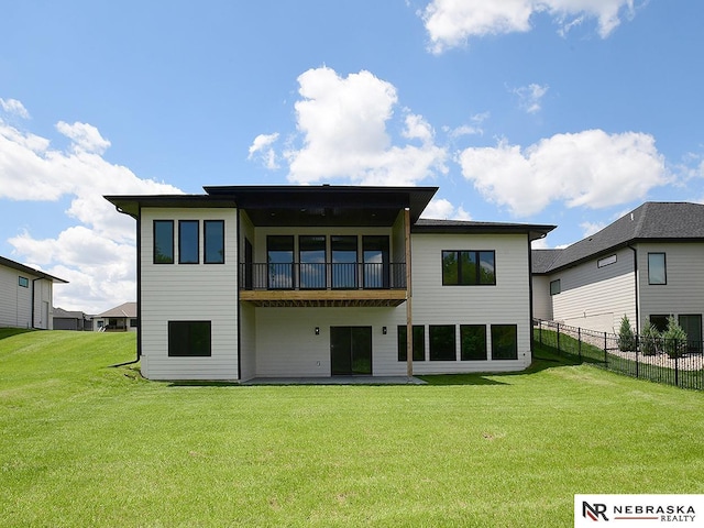 rear view of property featuring a lawn, fence, and a balcony